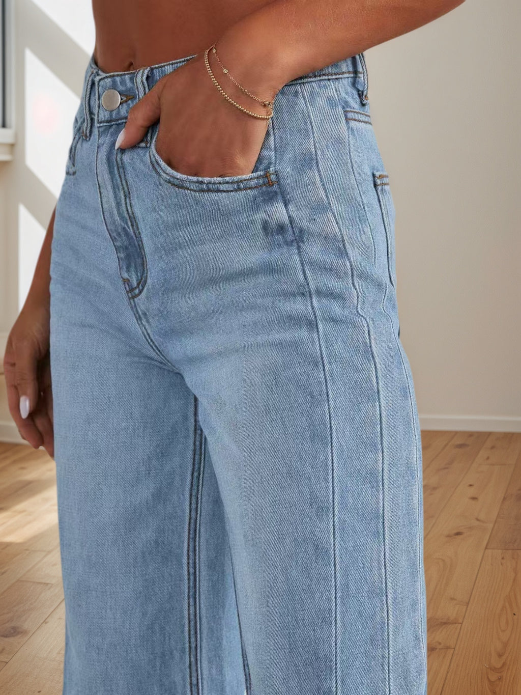 Light blue jeans worn by a person on a wooden floor.