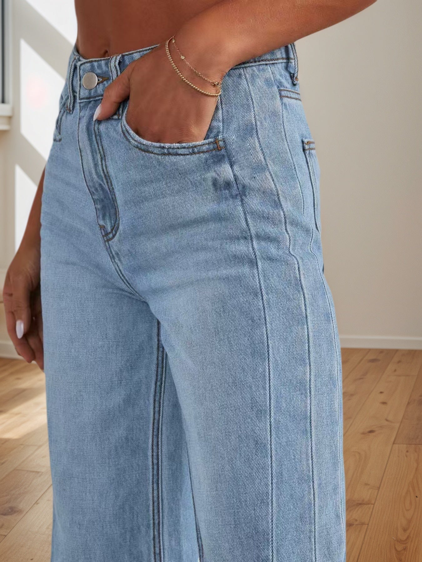 Light blue jeans worn by a person on a wooden floor.