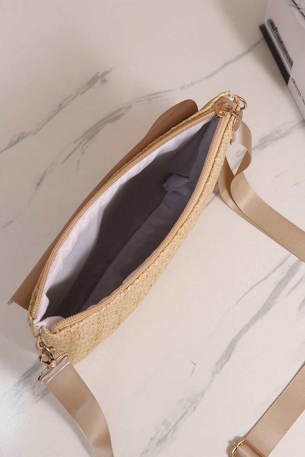 Beige handbag with a strap on a marble surface open view