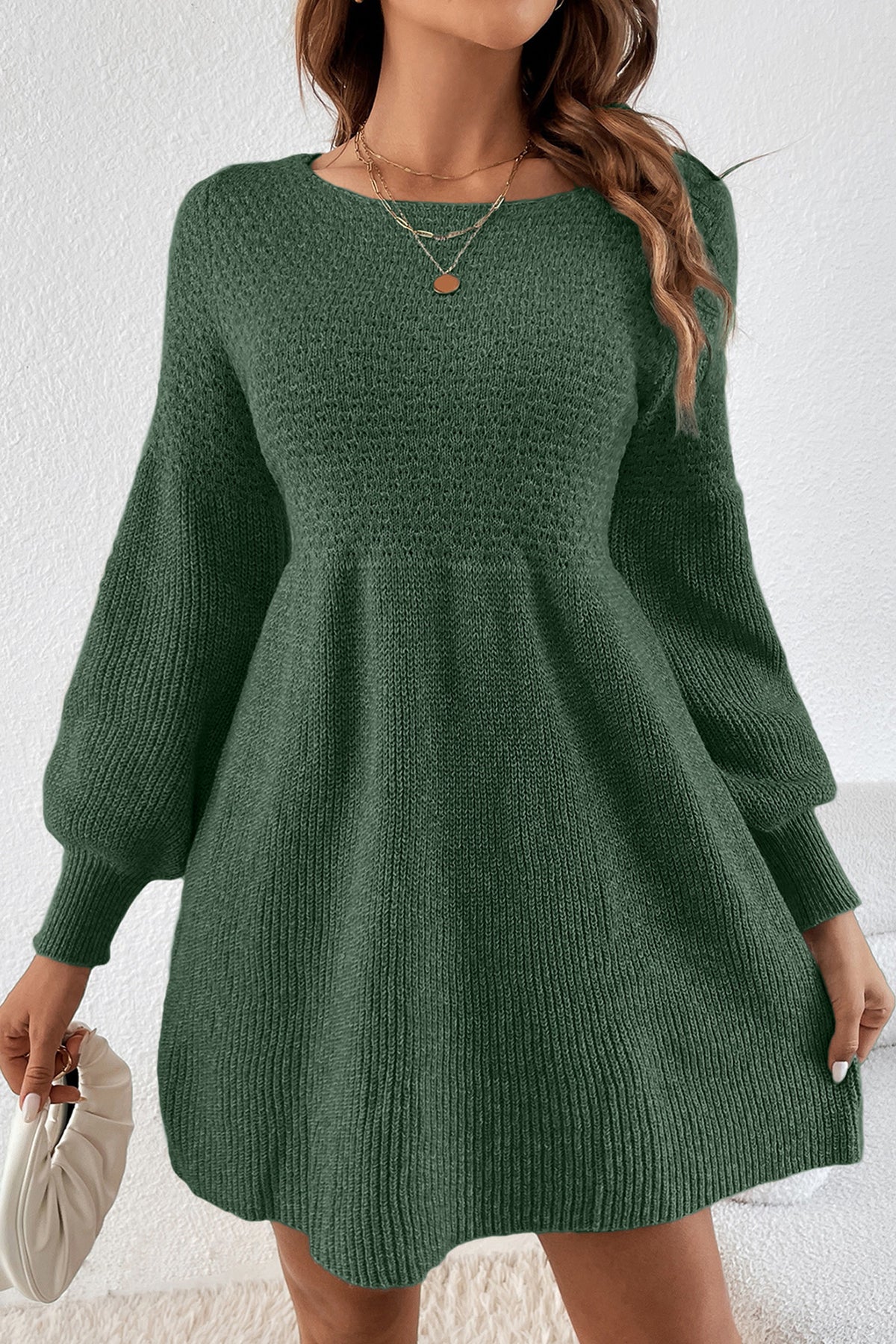 A woman wearing a mist green Empire Waist Lantern Sleeve Sweater Dress  with balloon sleeves, holding a white clutch purse.
