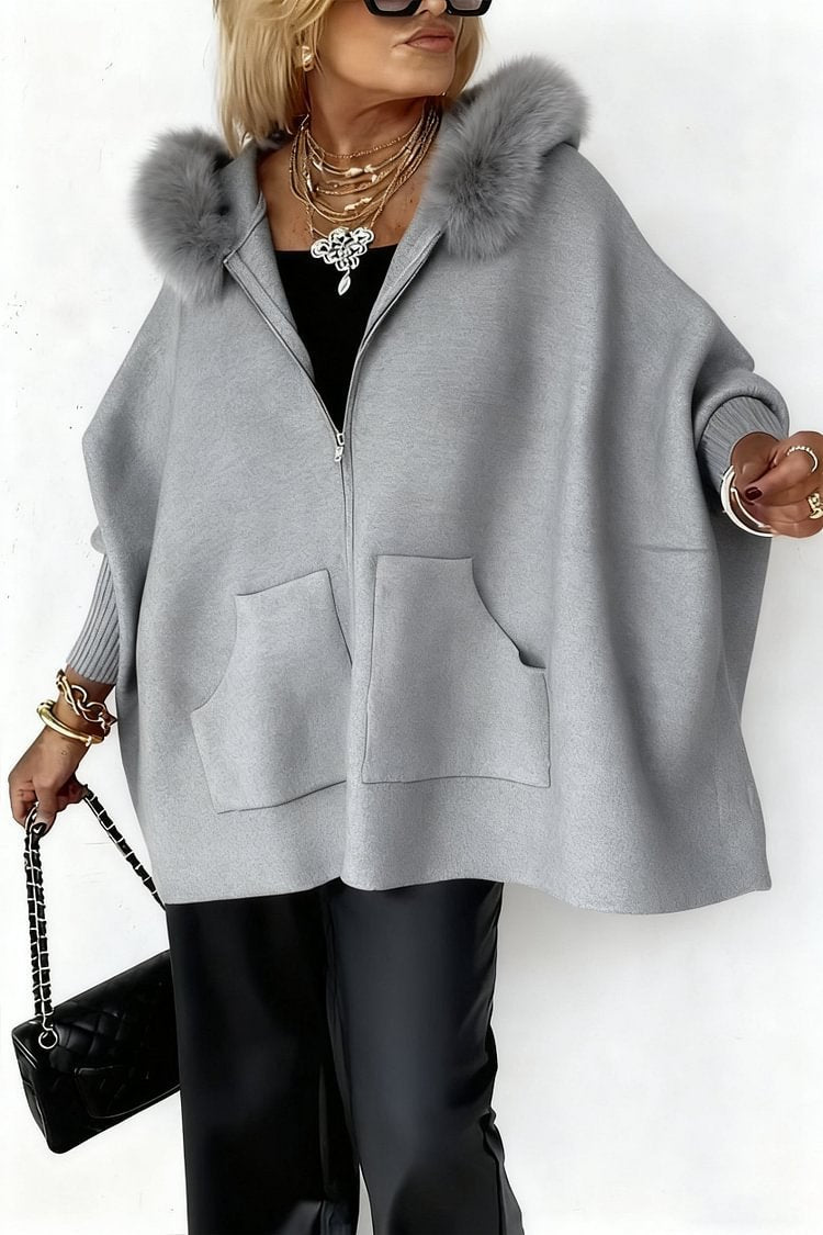 Person wearing a gray zip-up hoodie with fur hood on a white background