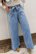 Person wearing blue wide-leg jeans with a white wall background