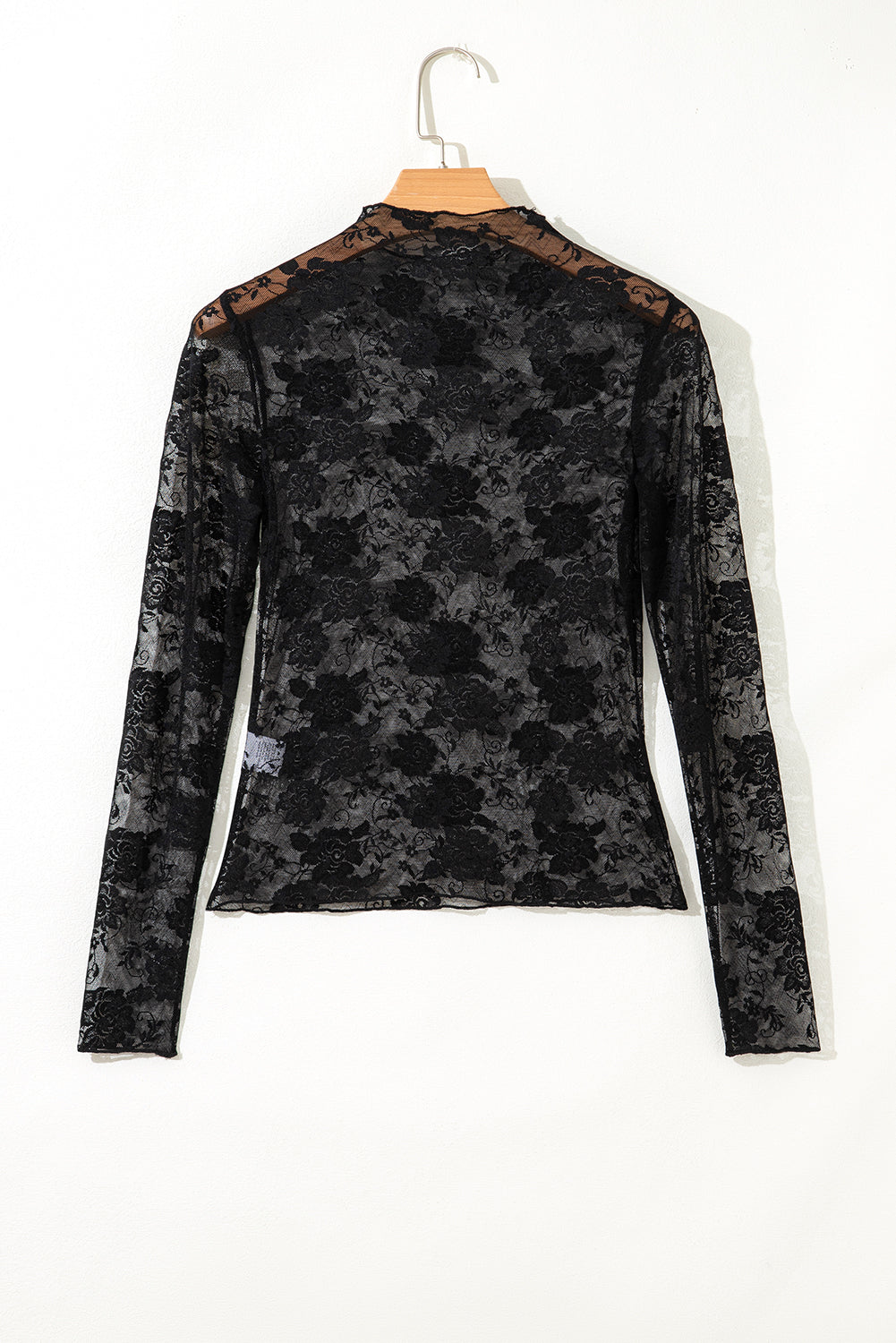 Black patterned long-sleeve top on a hanger against a white background
