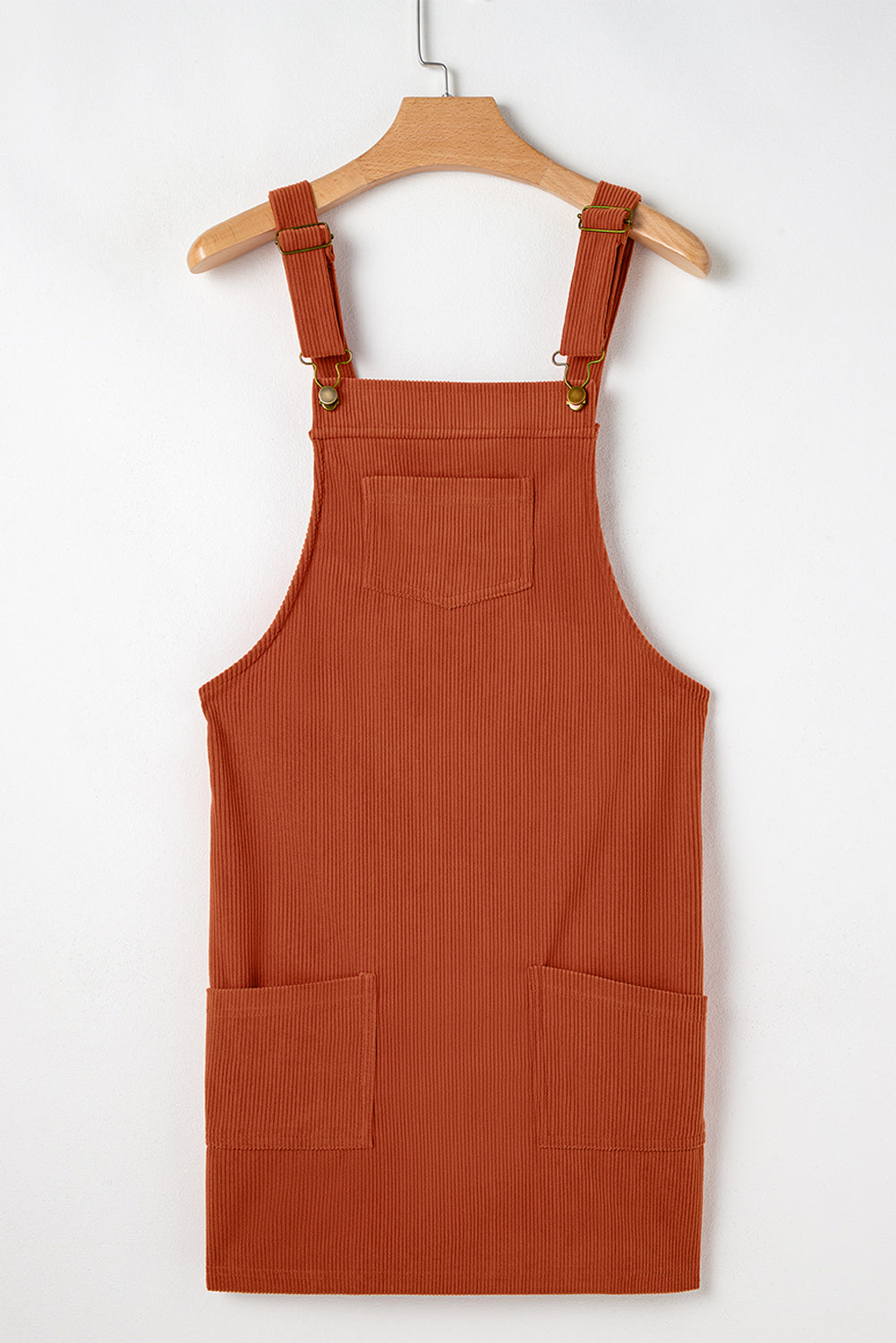 Brown corduroy pinafore dress on a hanger against a white background