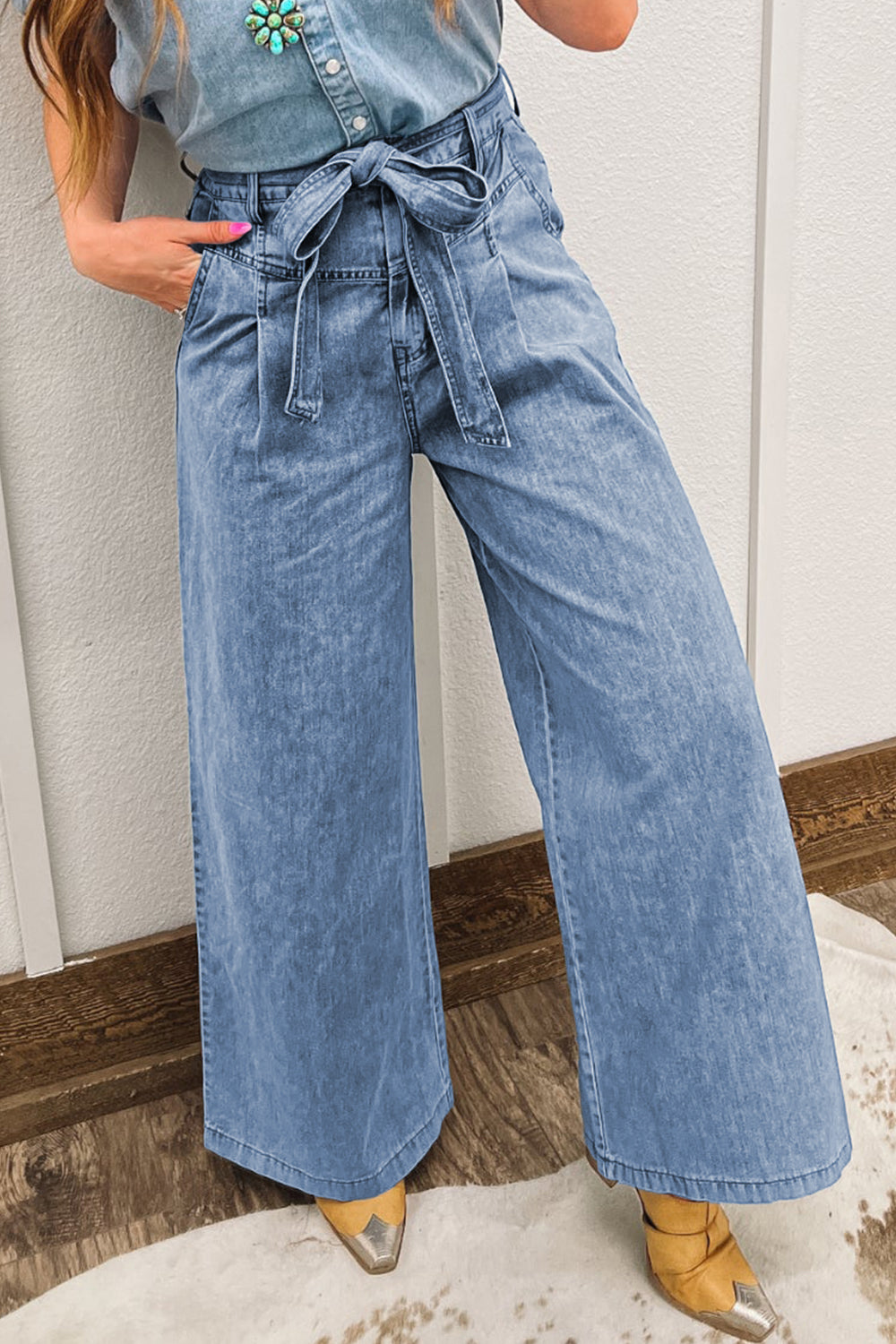 Person wearing a denim outfit with wide-leg pants and a tied waistband.