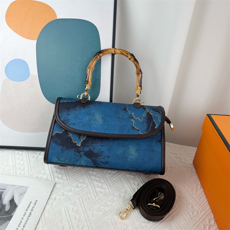 Blue handbag with a bamboo handle on a textured surface
