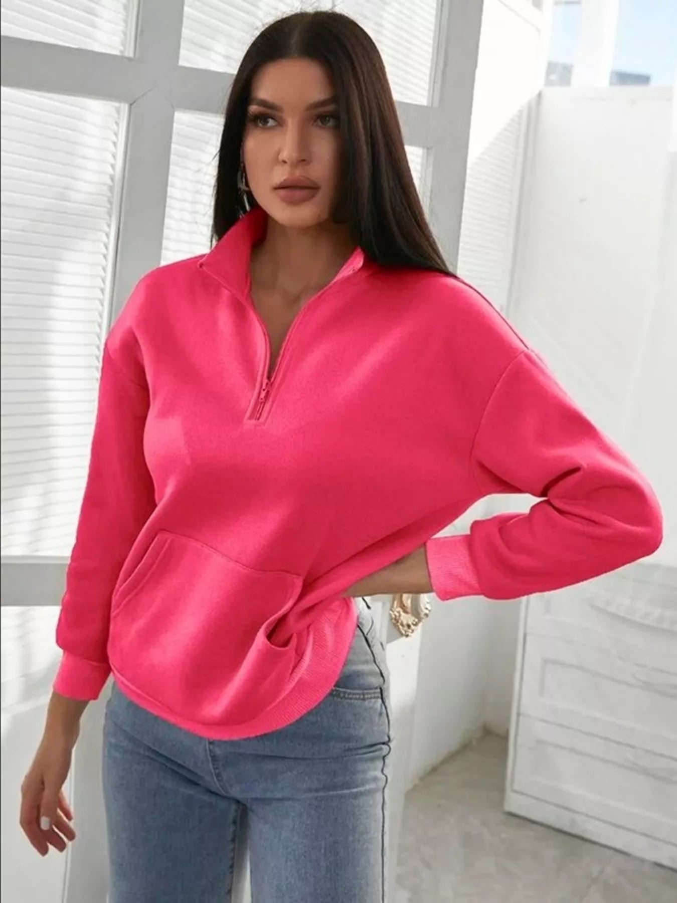 Person wearing a bright pink sweatshirt with a zipper in a bright room.