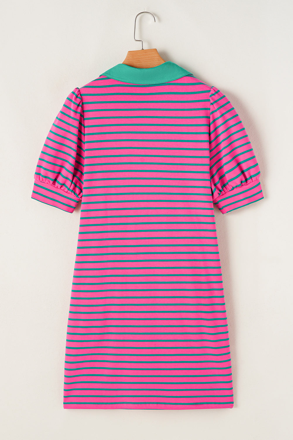 Pink and blue striped dress on a hanger against a white background