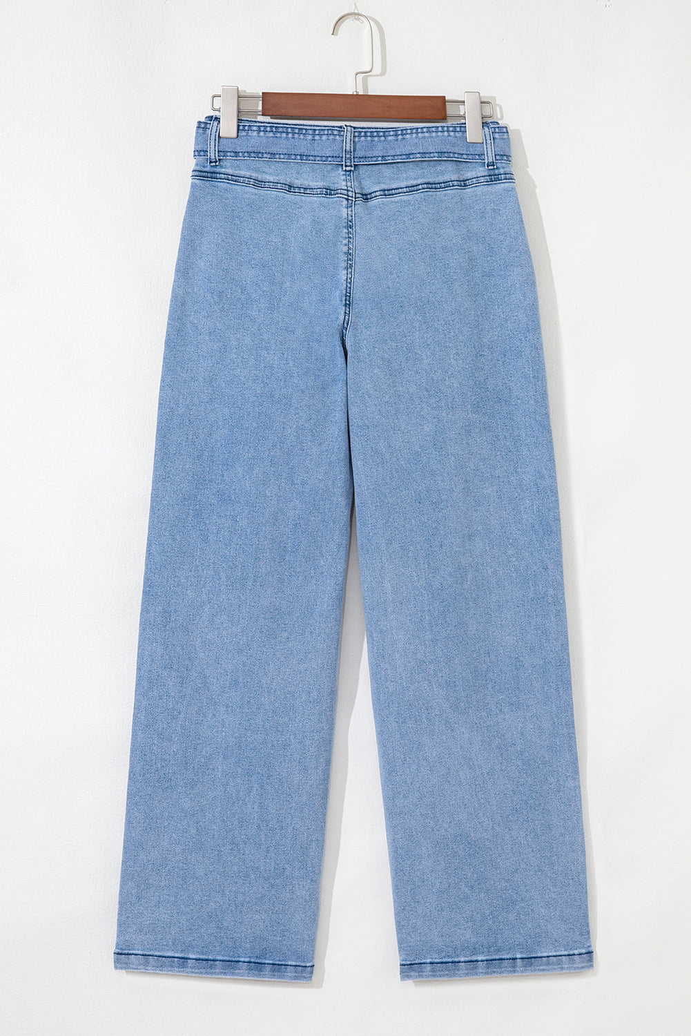 Light blue jeans on a hanger against a white background