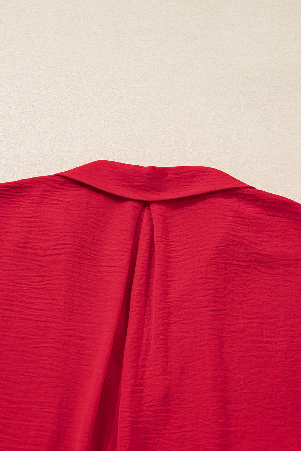 Close-up of a red garment with a collar on a beige background