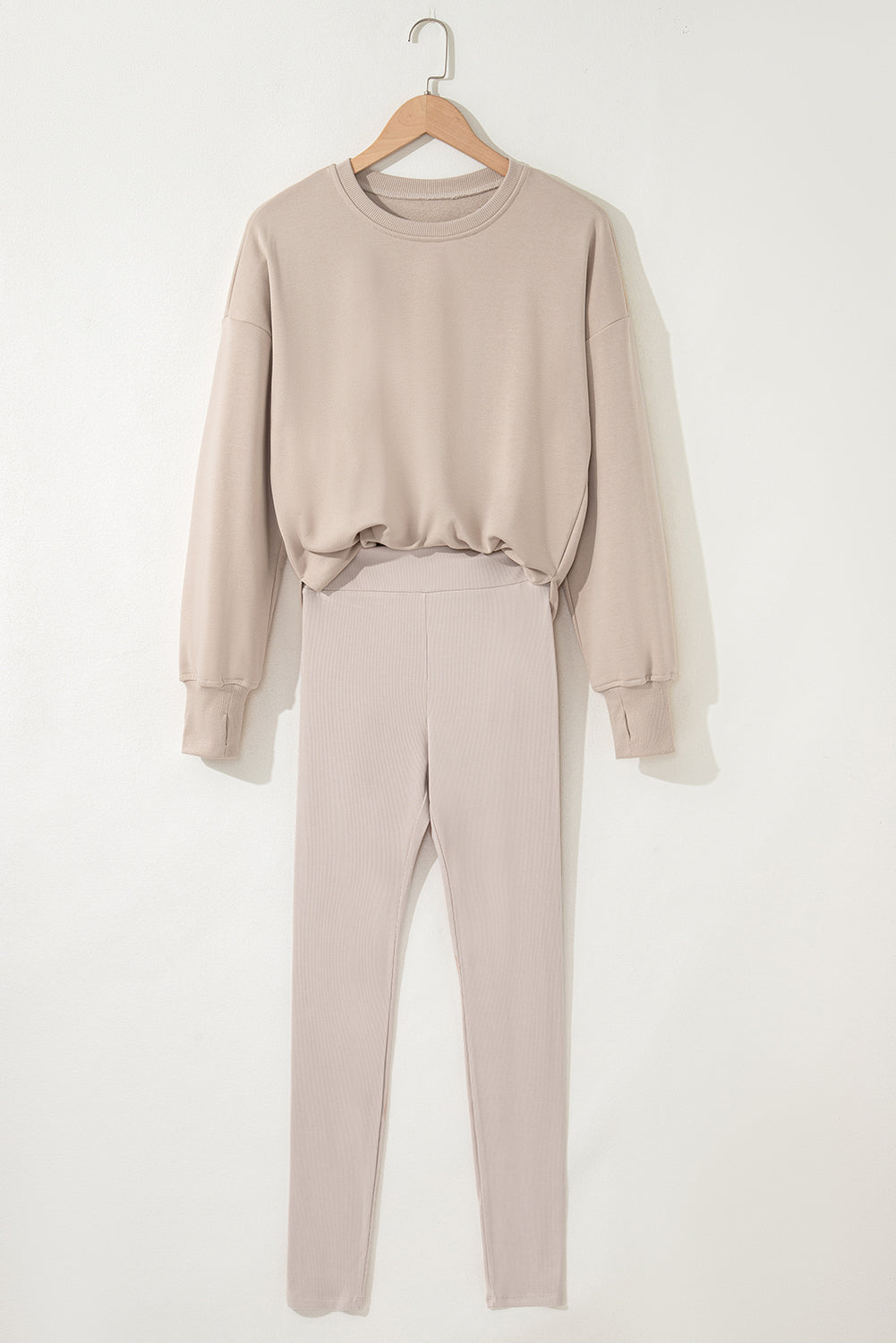 Beige sweatshirt and pants set on a hanger against a white background