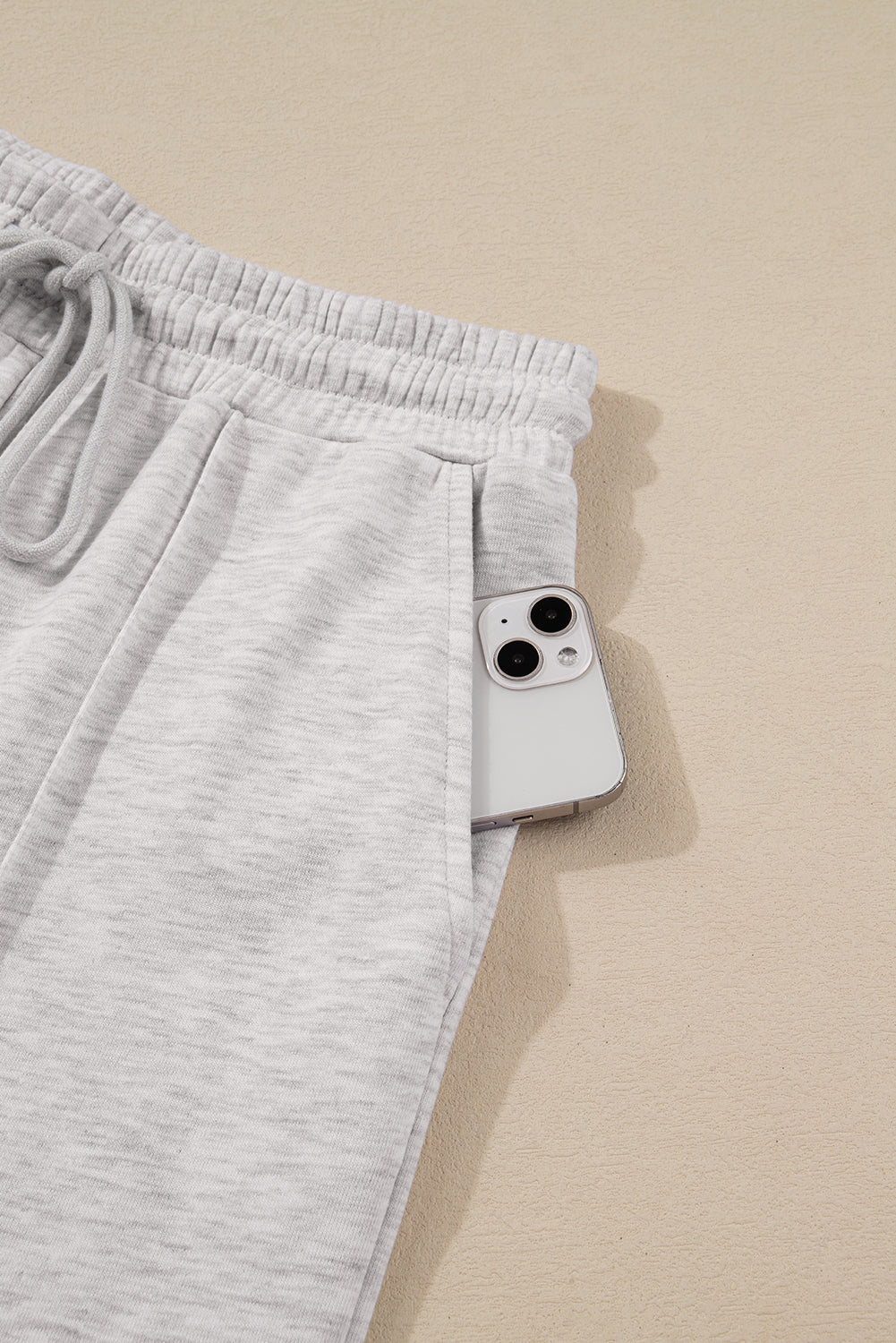 Gray sweatpants with a smartphone on a beige surface