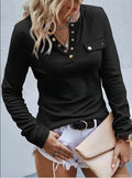 Woman wearing a black long-sleeve top with buttons, white shorts, and holding a beige clutch against a light gray background.