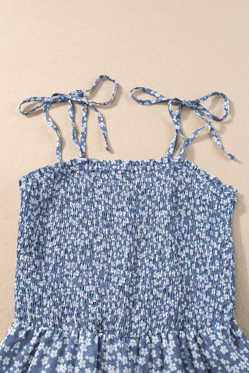 Blue floral dress with tied straps on a beige background