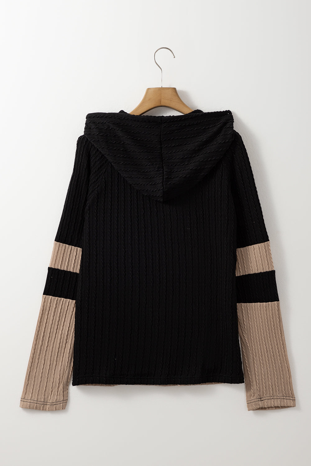 Black and beige ribbed sweater on a hanger against a white background