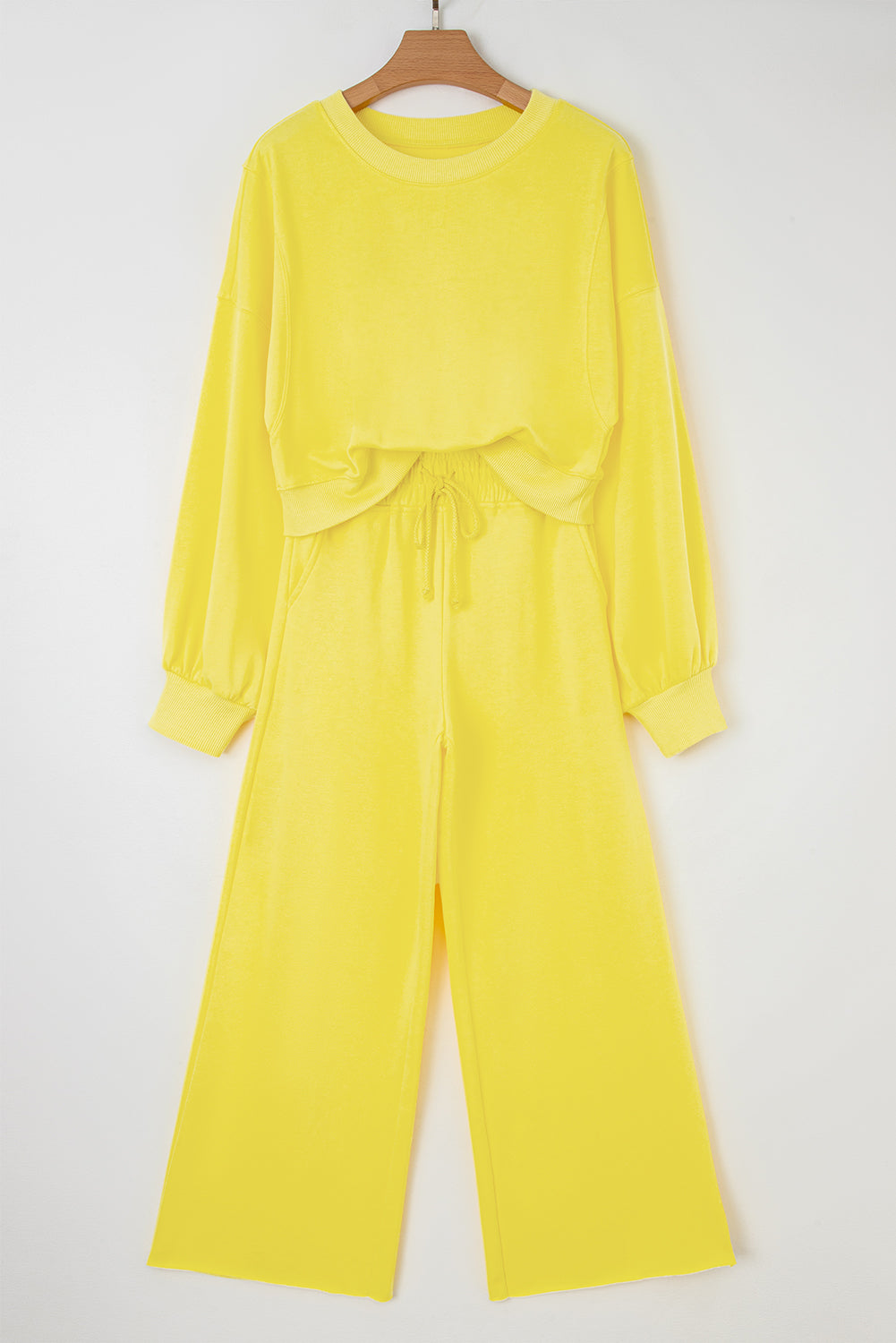 Yellow outfit with long-sleeve top and wide-leg pants on a hanger against a white background