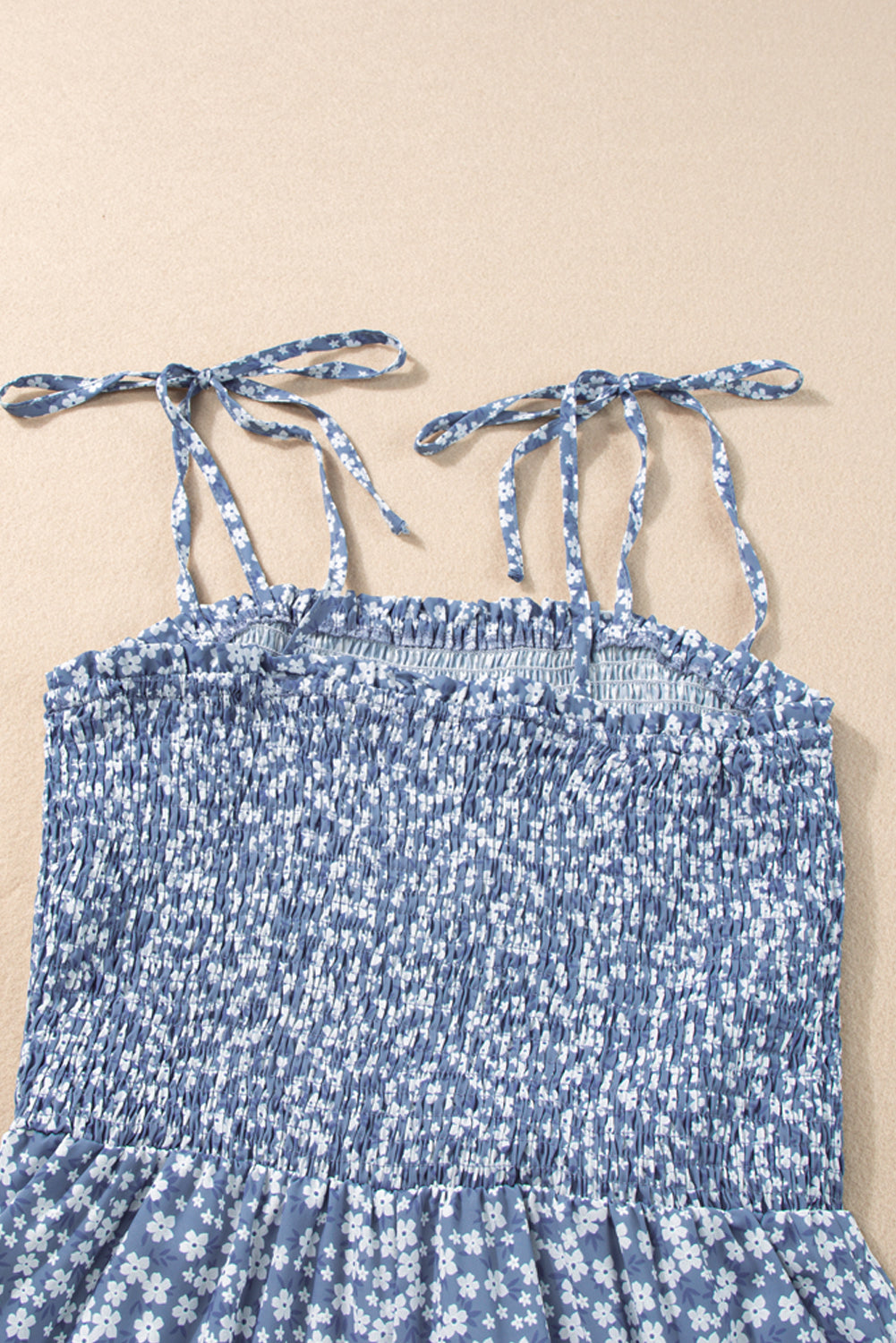 Blue floral dress with tied straps on a beige background