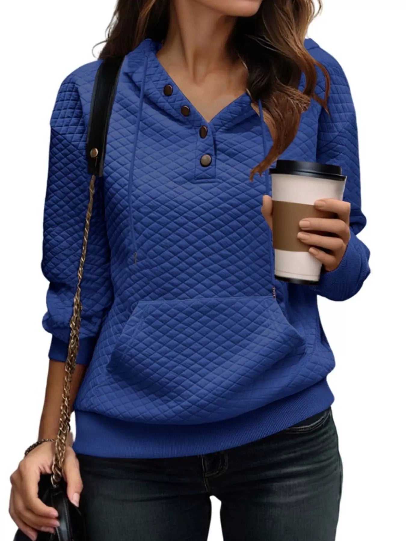 Woman wearing a blue quilted jacket holding a coffee cup on a white background