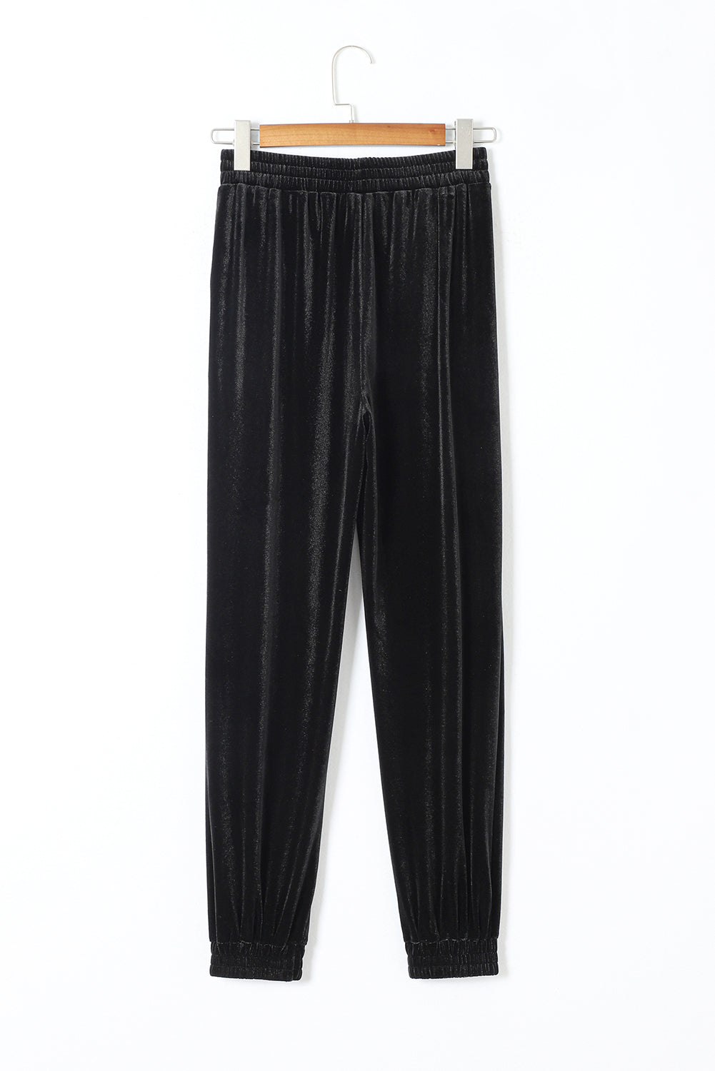 Black velvet pants on a hanger against a white background