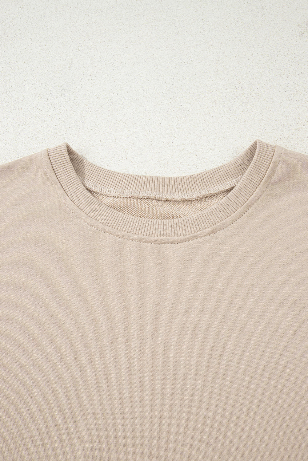 Close-up of a beige sweater with a textured fabric texture on a light background