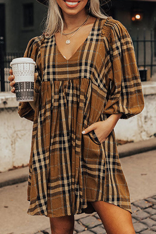 Woman wearing a plaid dress holding a coffee cup outdoors.