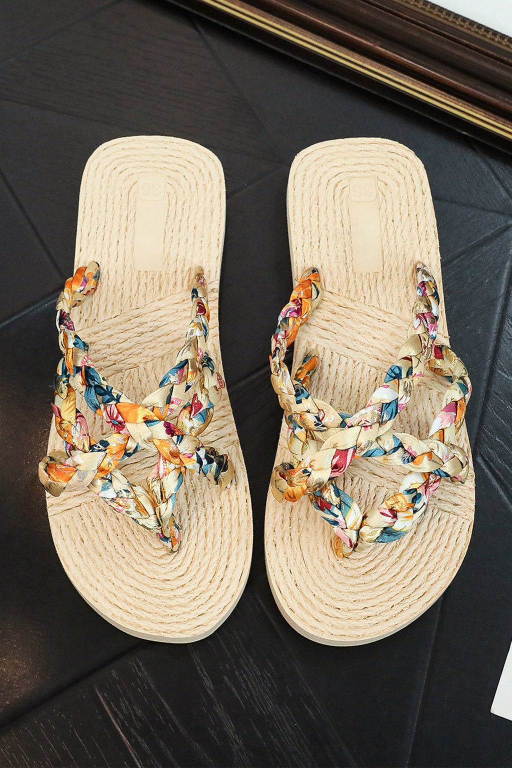 Pair of sandals with colorful floral straps on a dark surface