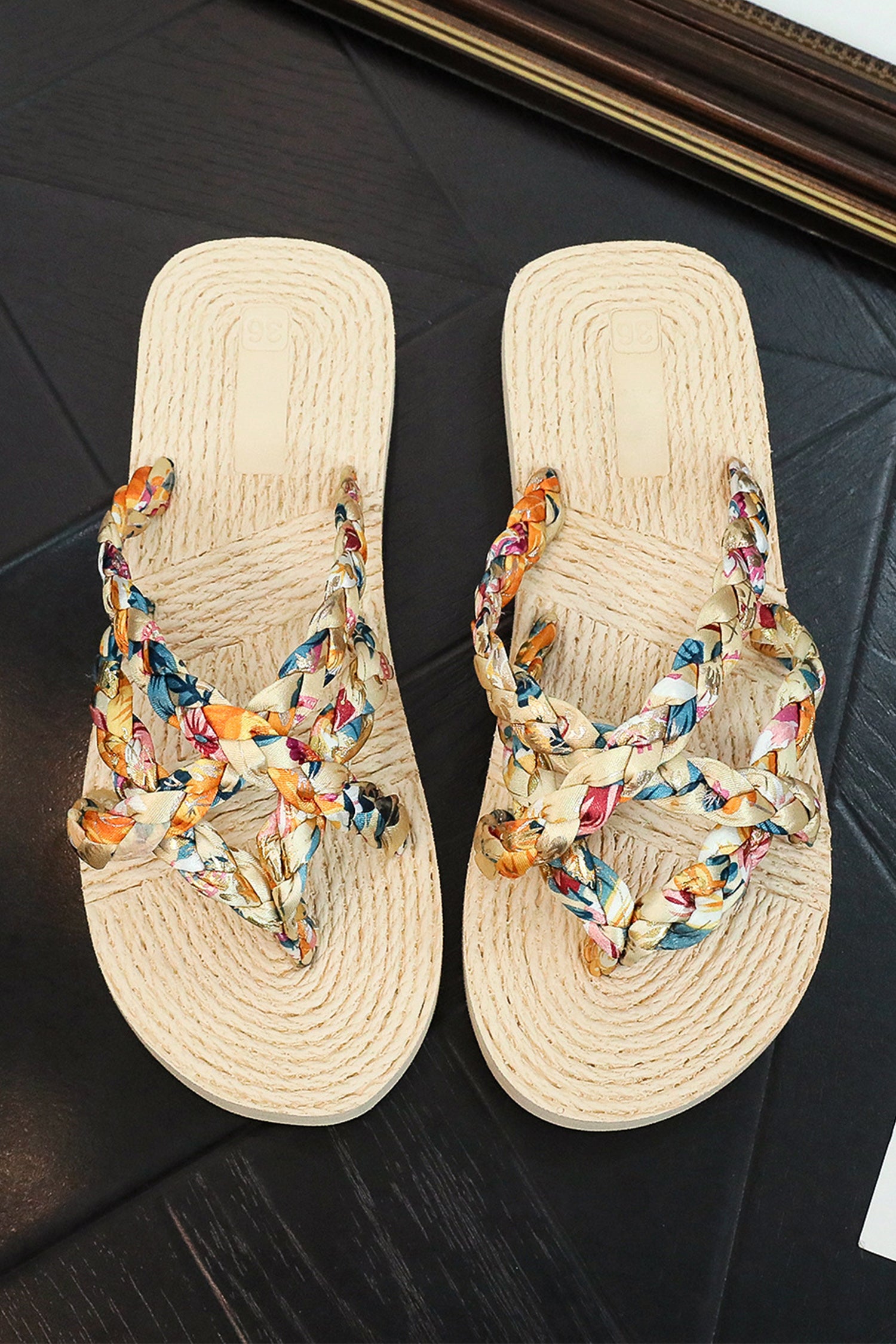 Pair of sandals with colorful floral straps on a dark surface