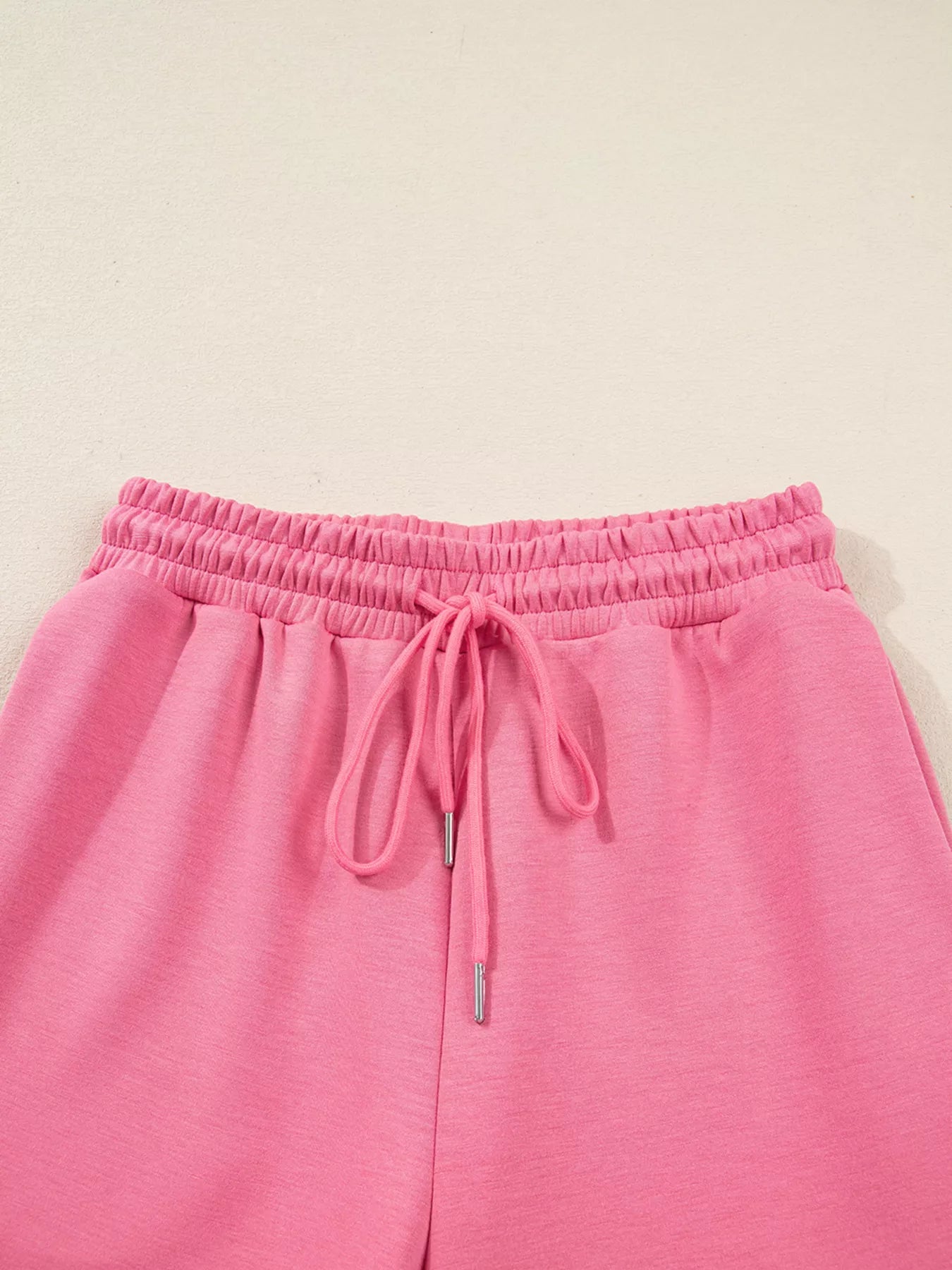 Pink sweatpants with drawstring on a beige background