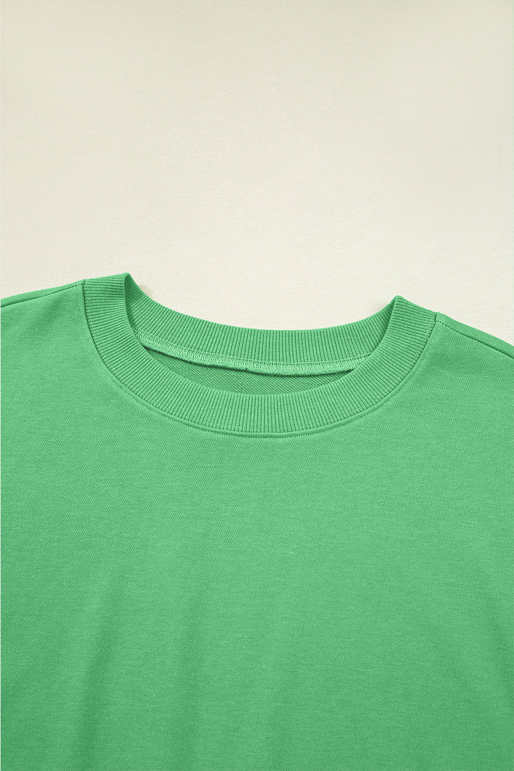 Close-up of a green sweater with a beige background