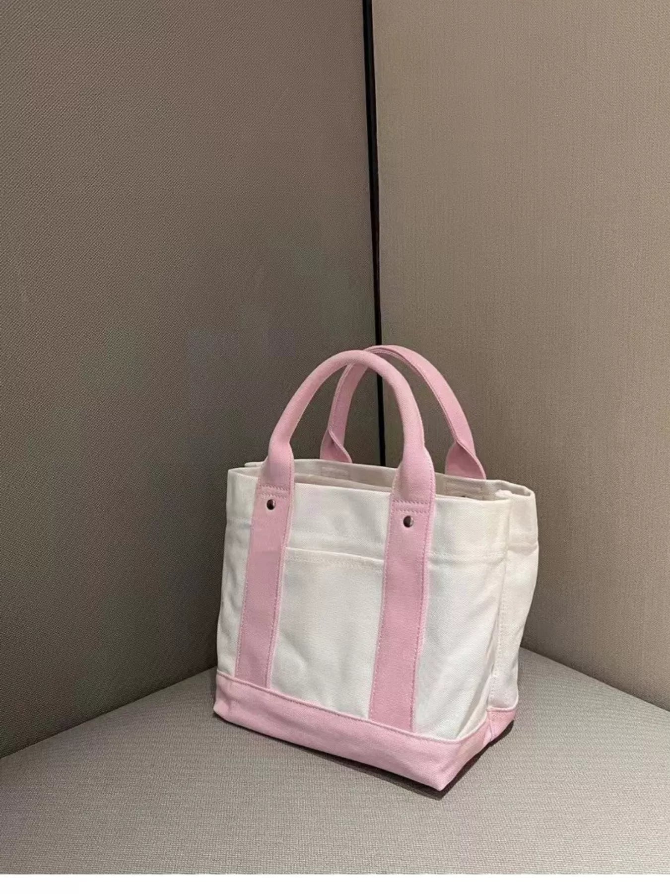 White tote bag with pink handles and trim on a neutral background