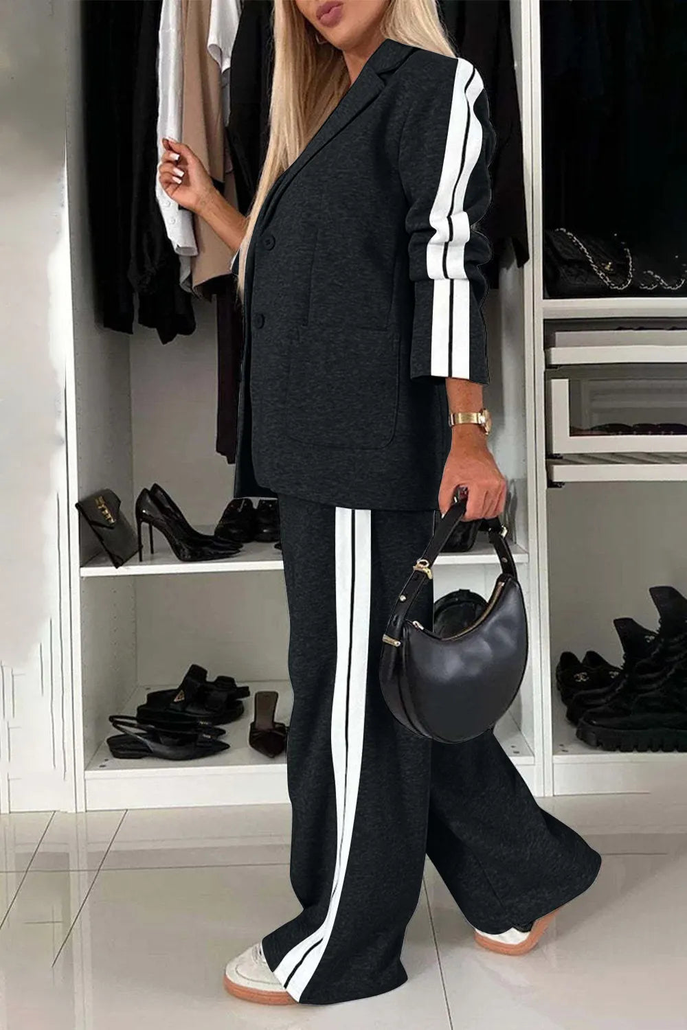 Person wearing a black outfit with white stripes in a room with shelves of shoes.