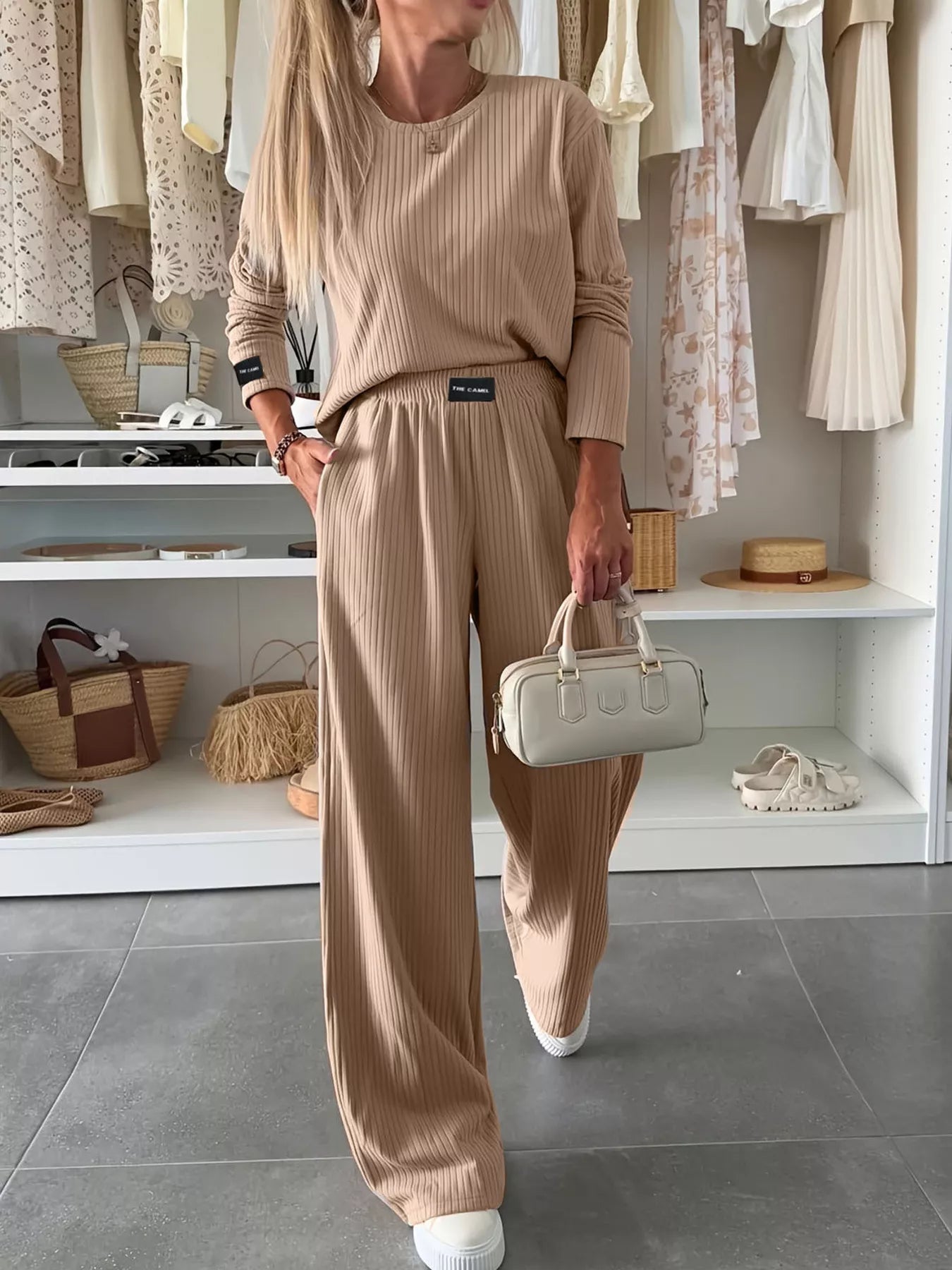 Woman in a beige outfit holding a small handbag in a store setting