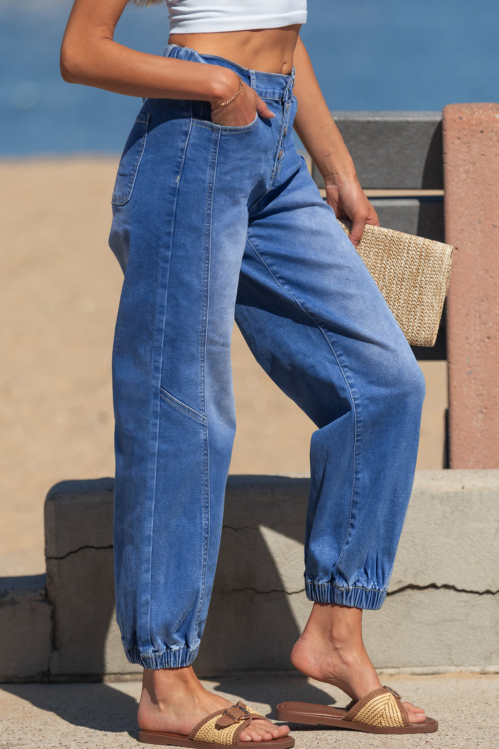 A model wearing Blue Tapered Jeans with a button fly and cuffed harem-style legs side view