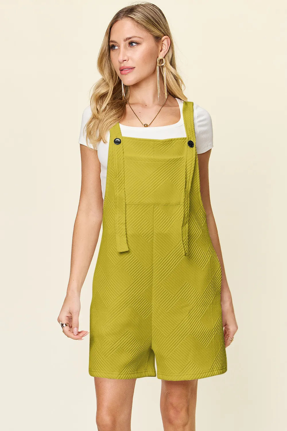 Woman wearing a green pinafore dress on a beige background