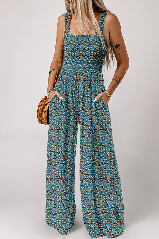 Woman wearing a teal floral jumpsuit on a plain background