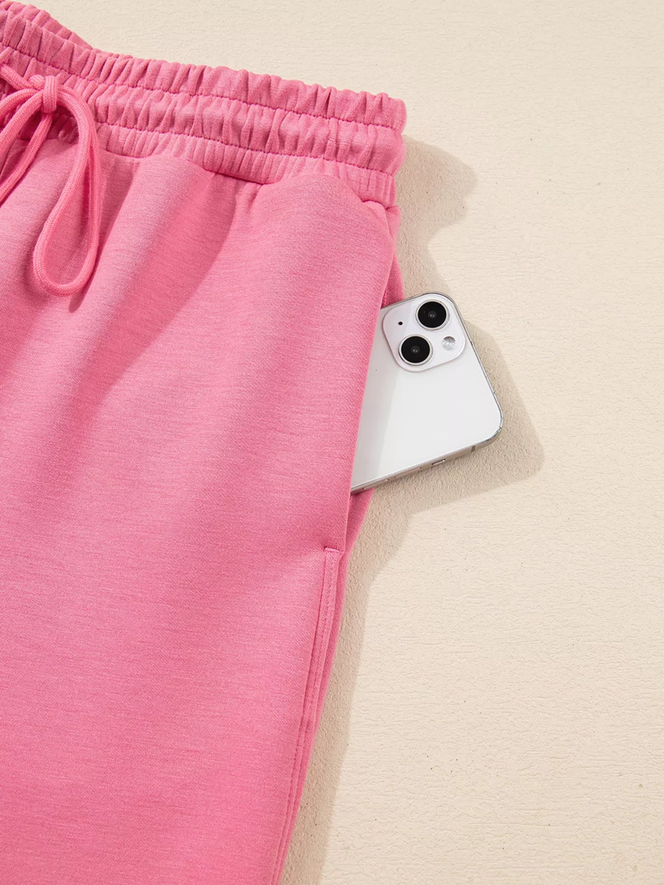 Pink shorts with a smartphone on a beige background