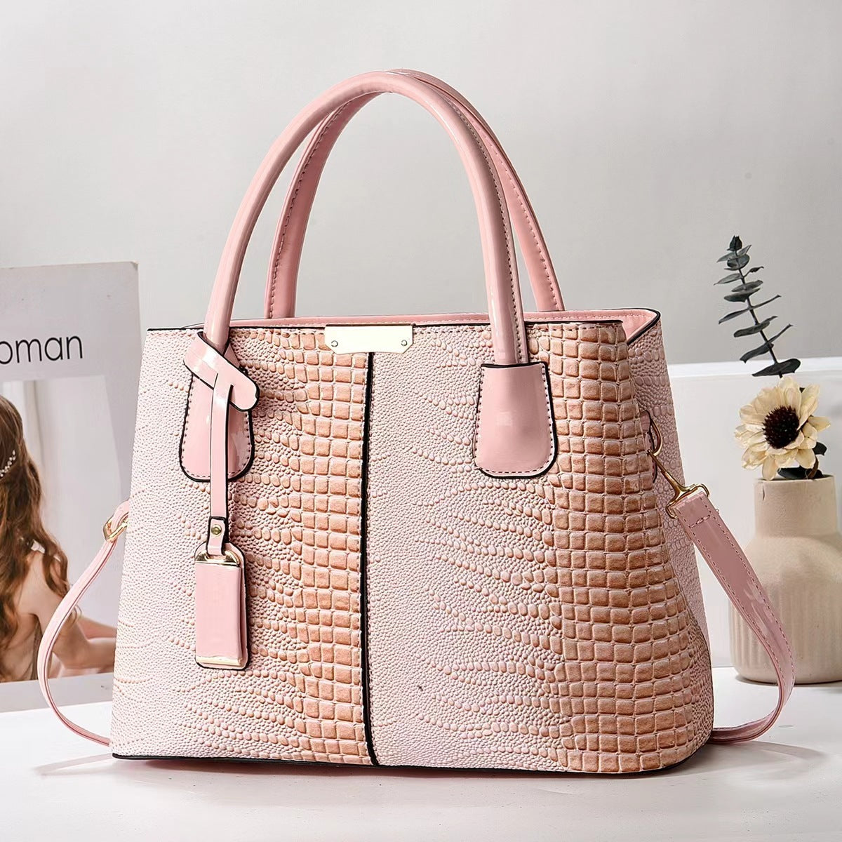 Pink textured handbag on a light surface with a neutral background