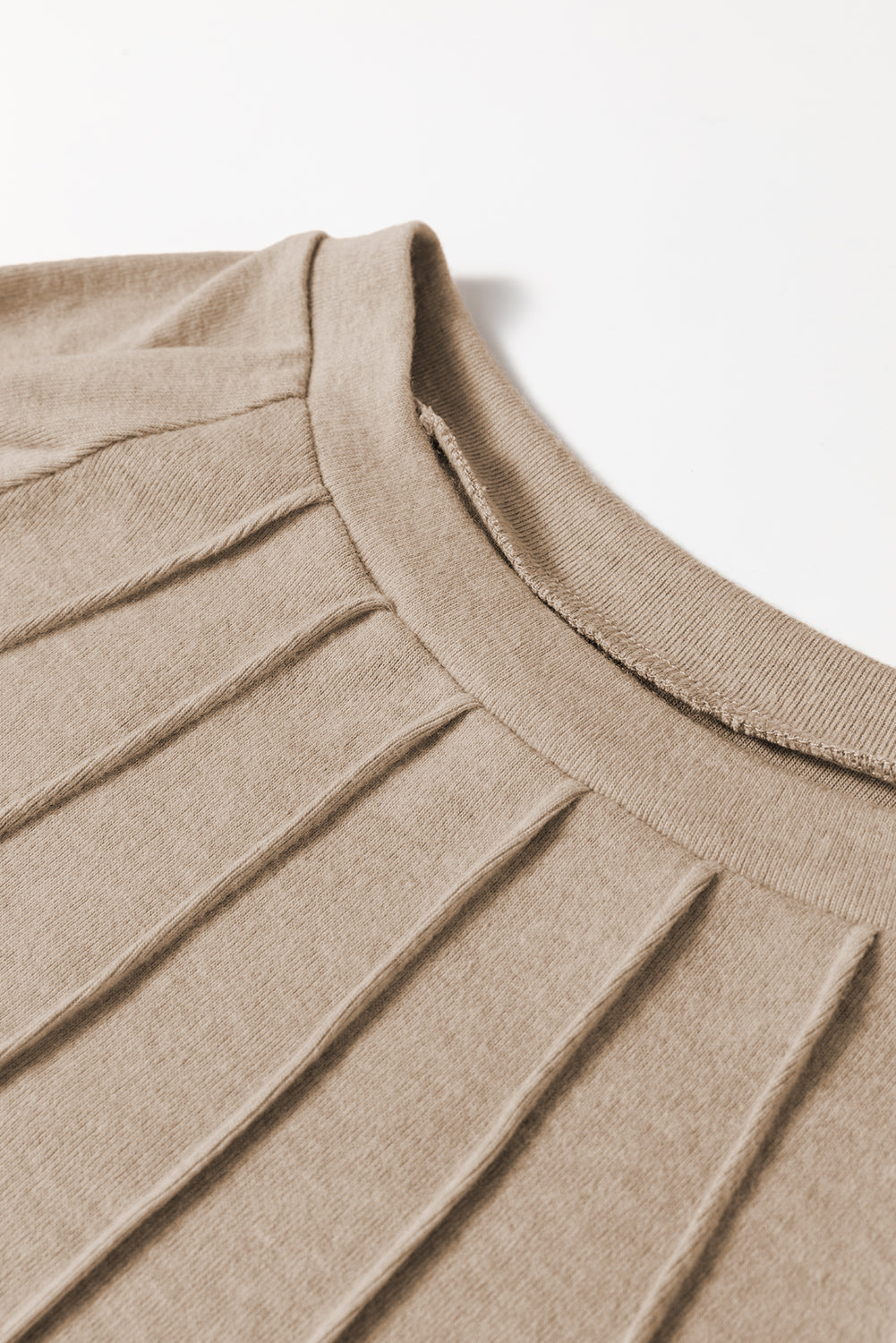 Close-up of a beige sweater with ribbed texture on a white background