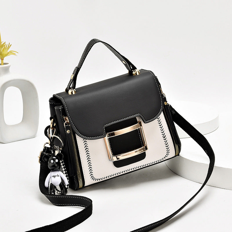 Black and white handbag with gold accents on a white background