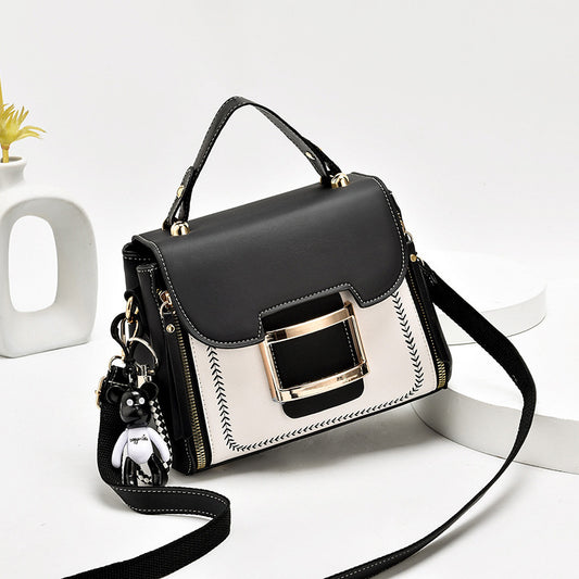 Black and white handbag with gold accents on a white background