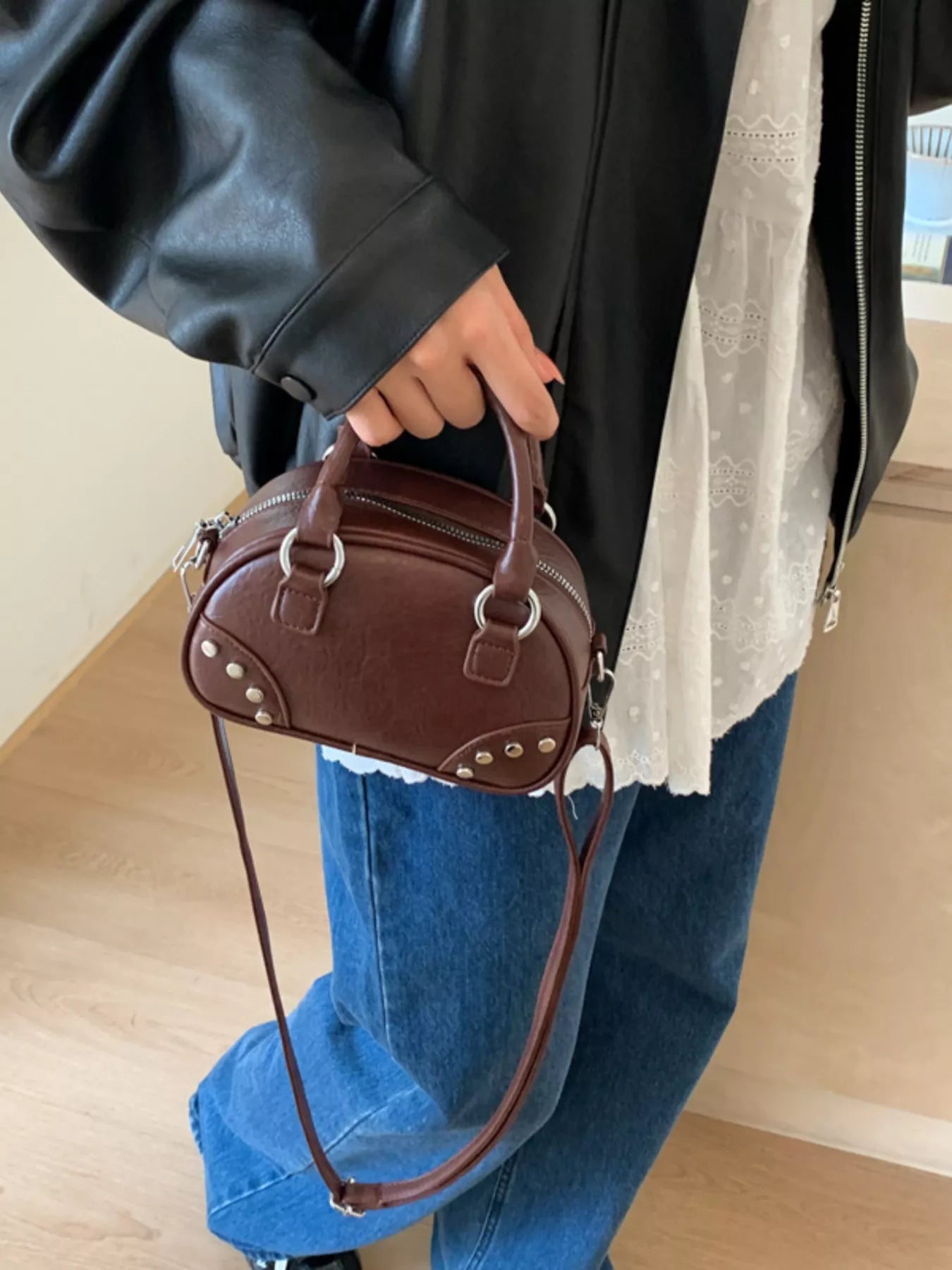 Person holding a brown handbag with a neutral background