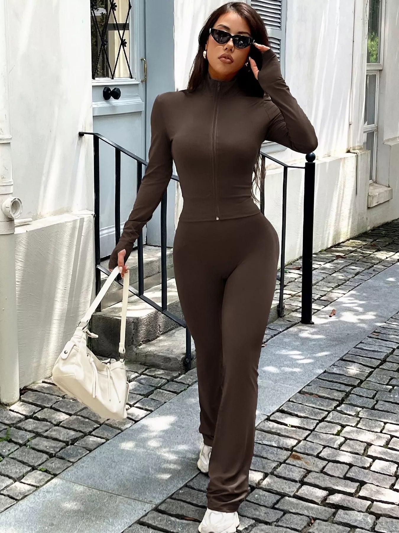 Woman in a brown outfit walking outdoors on a sunny day.