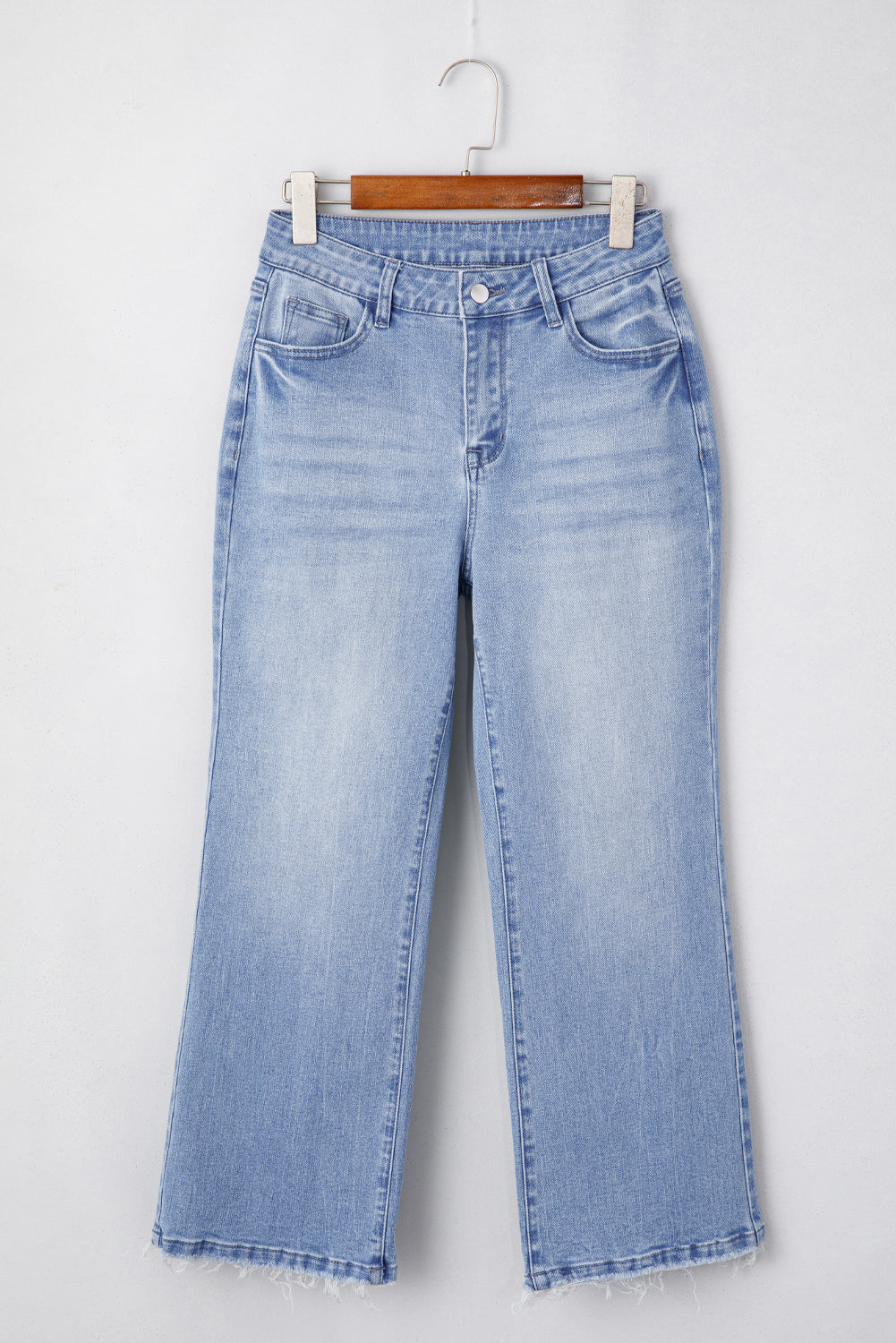 Light blue jeans on a hanger against a white background