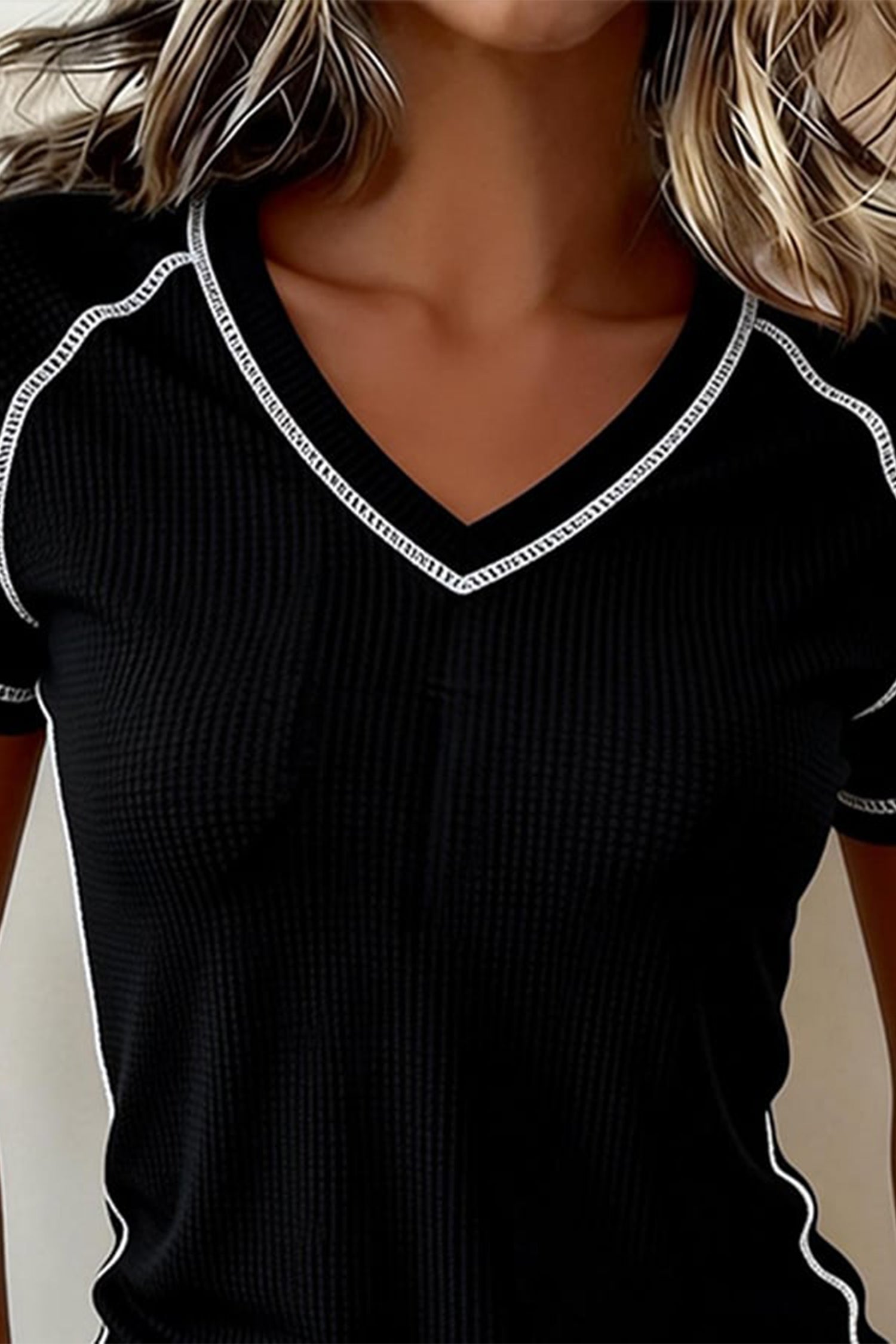 Black ribbed sweater with white trim worn by a person close-up