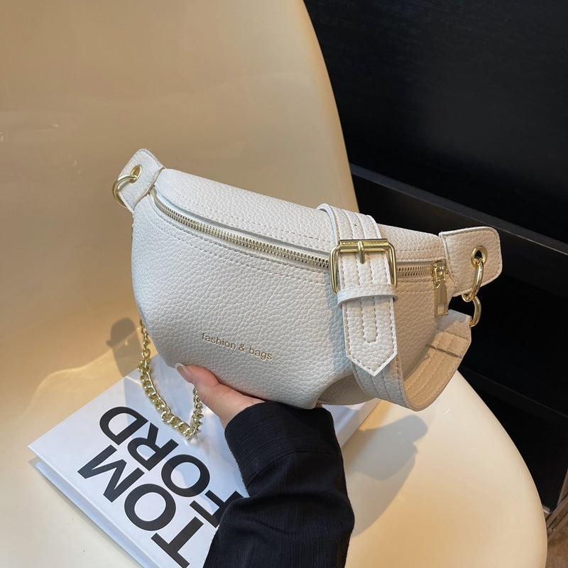 White waist bag with gold accents held by a hand on a blurred background