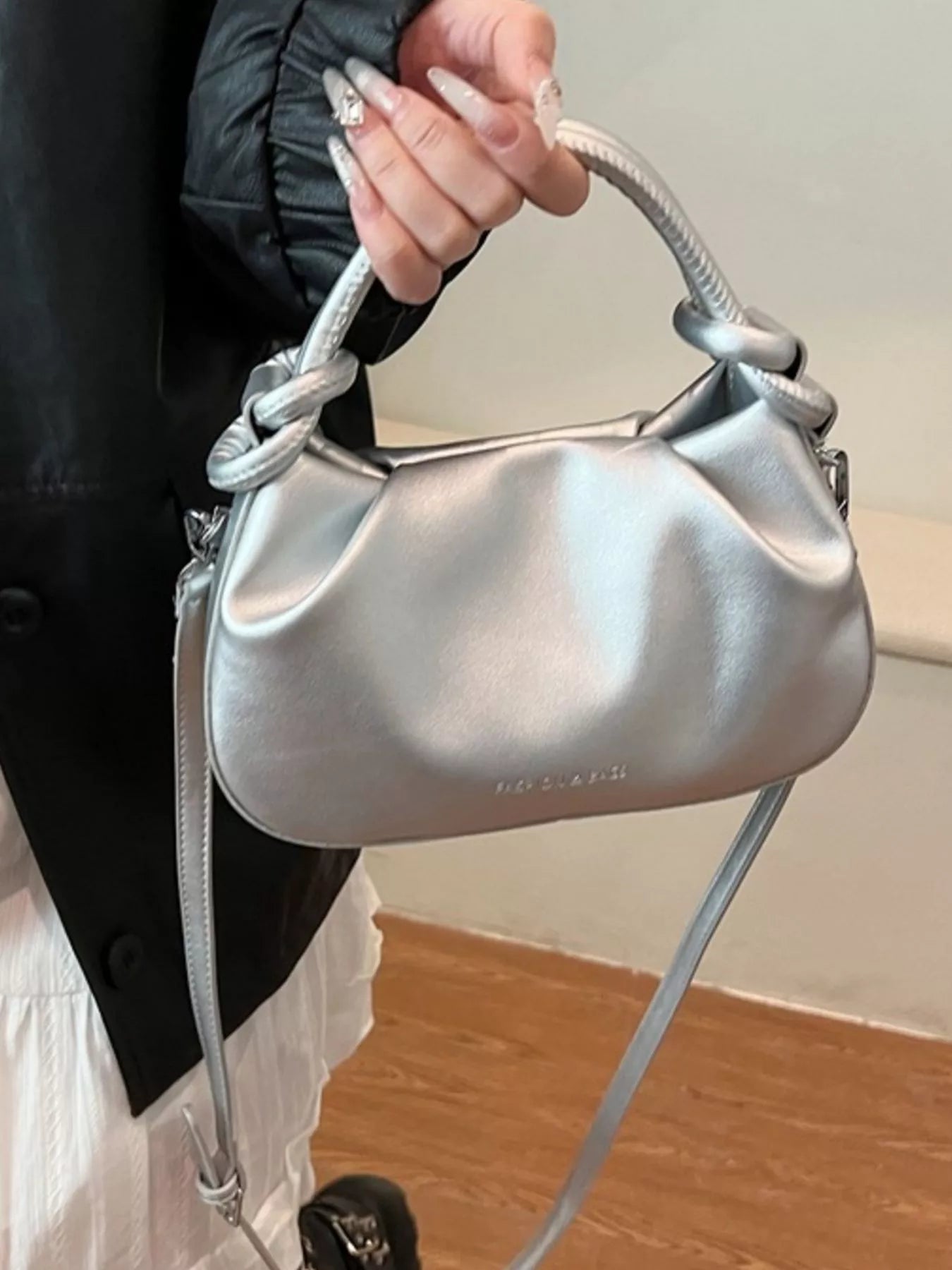 Silver handbag held by a person with a blurred background