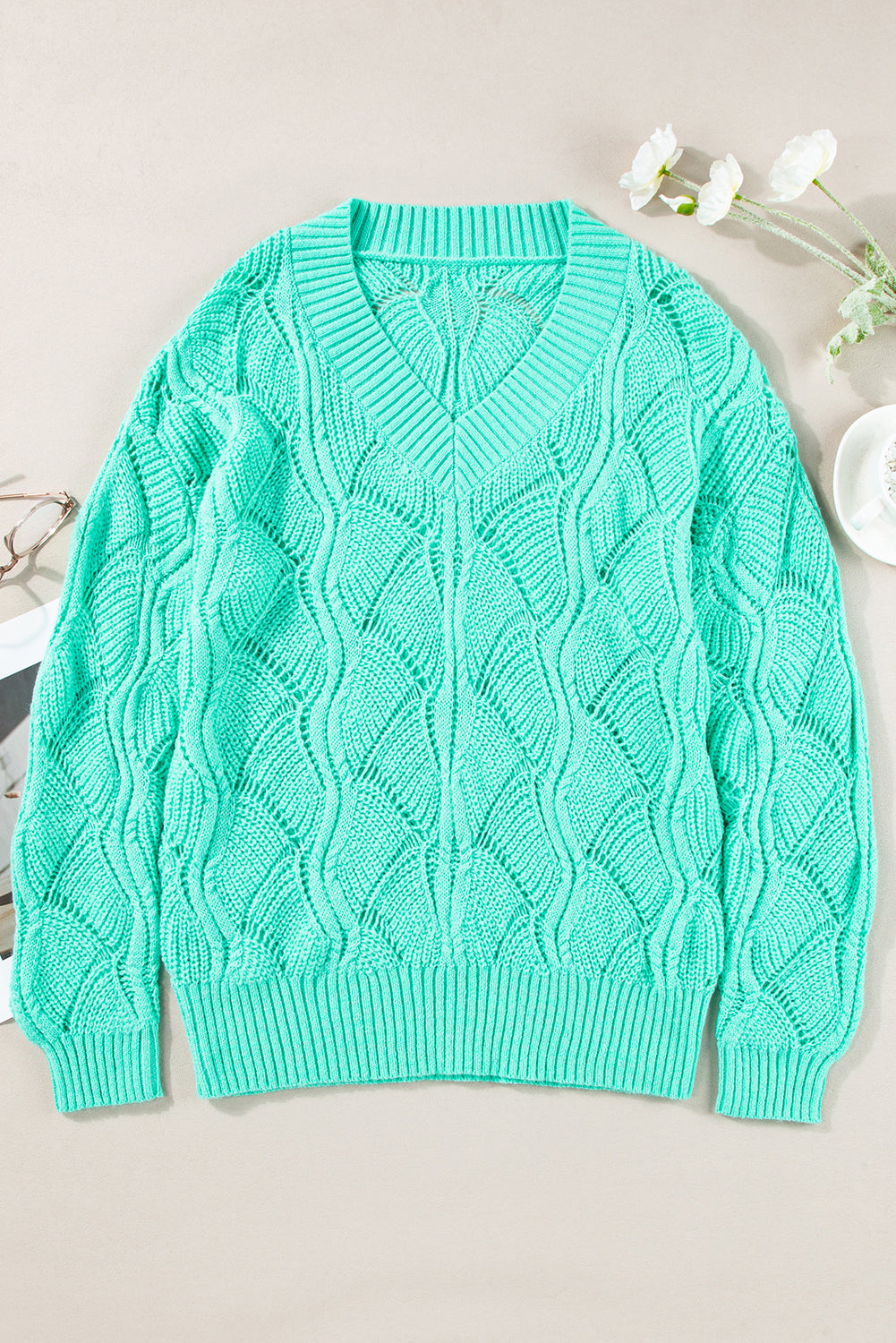 Teal cable knit sweater on a light background