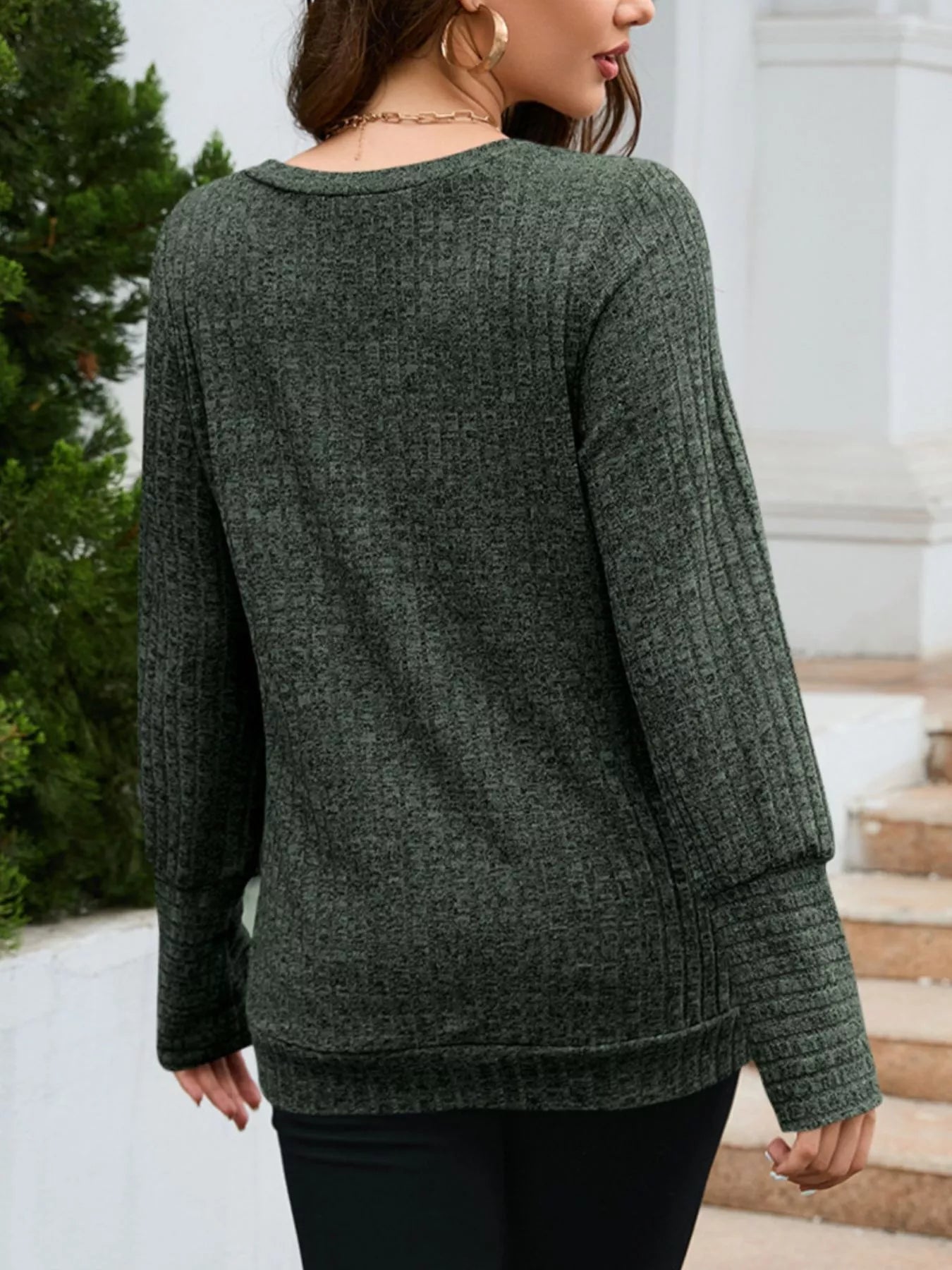 Person wearing a green sweater with a blurred background