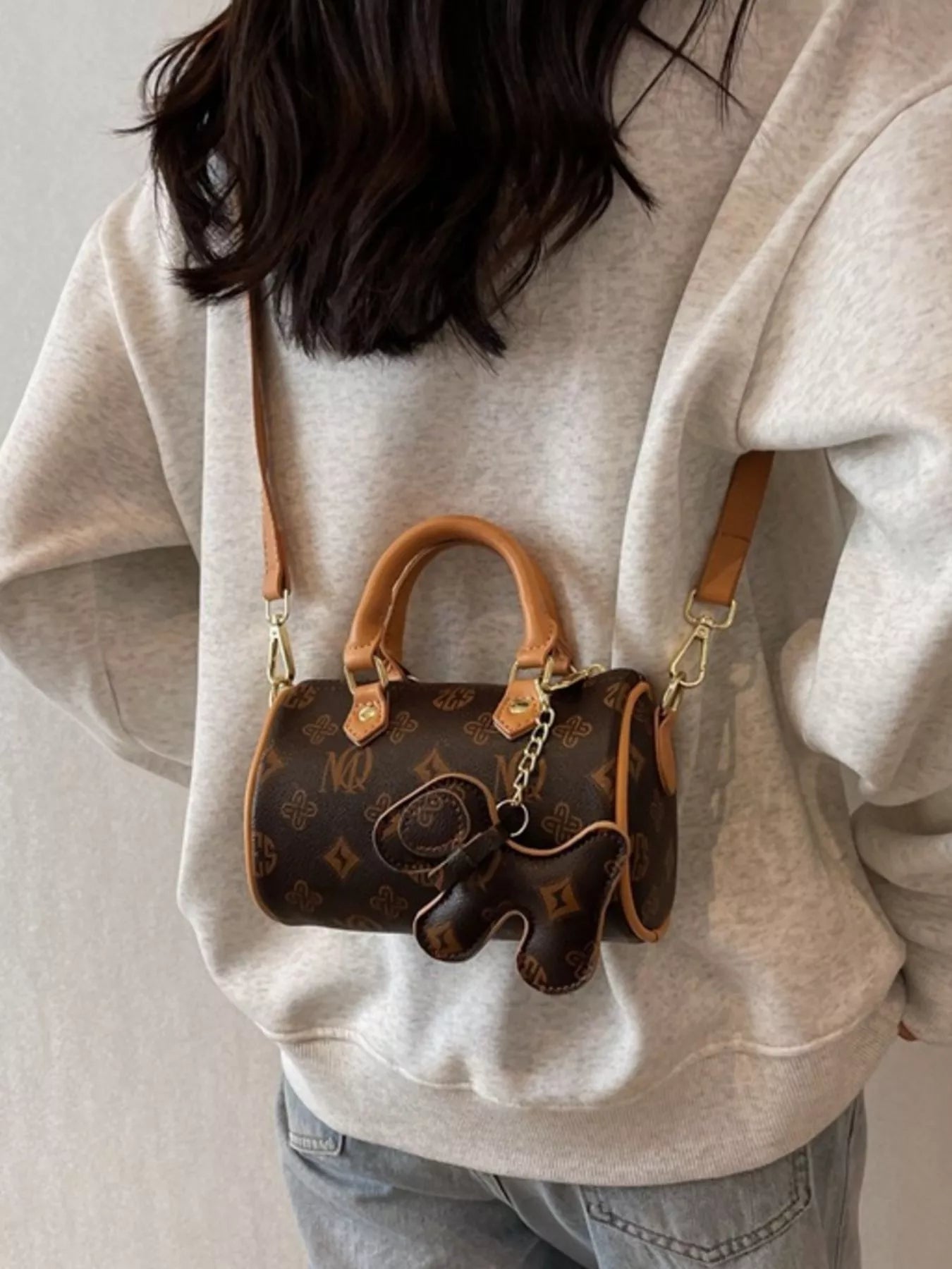 Person wearing a beige hoodie with a brown leather handbag over their shoulder.