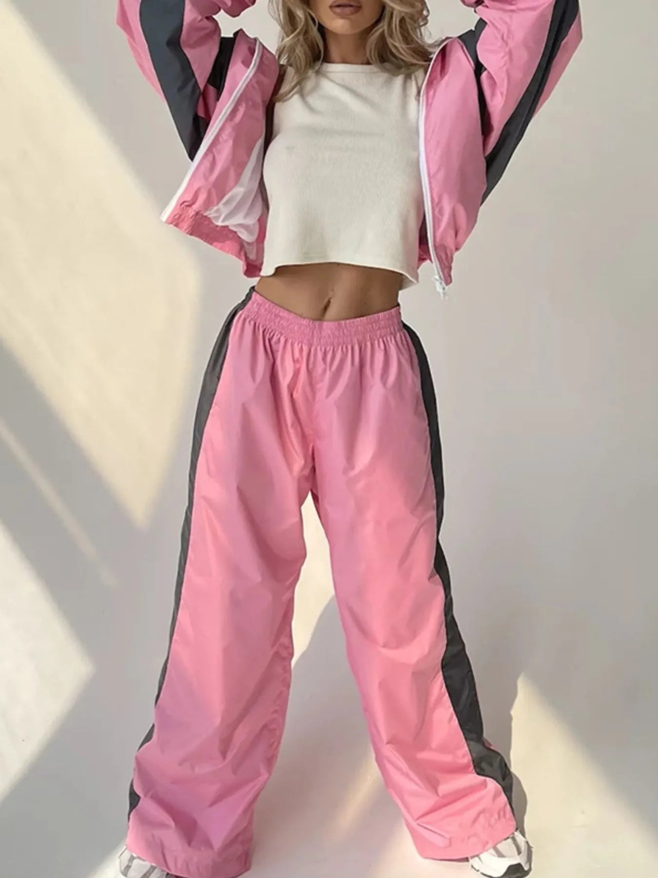 Person wearing a pink and black tracksuit with a white top against a neutral background
